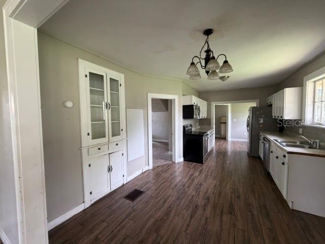 A kitchen features white cabinetry, a built-in hutch, dark wood-look flooring, and a chandelier — 3510 N FLORIDA AVENUE, LAKELAND, FL