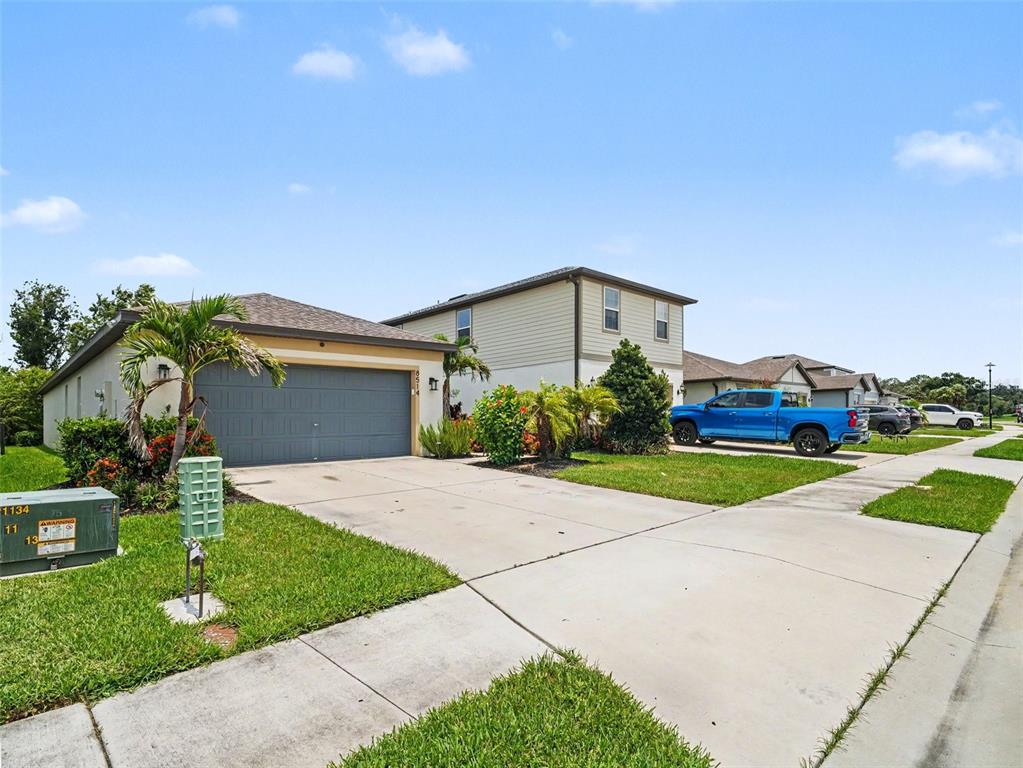 A single-story house with a gray garage and a driveway sits next to a two-story home — 8514 ABALONE LOOP, PARRISH, FL