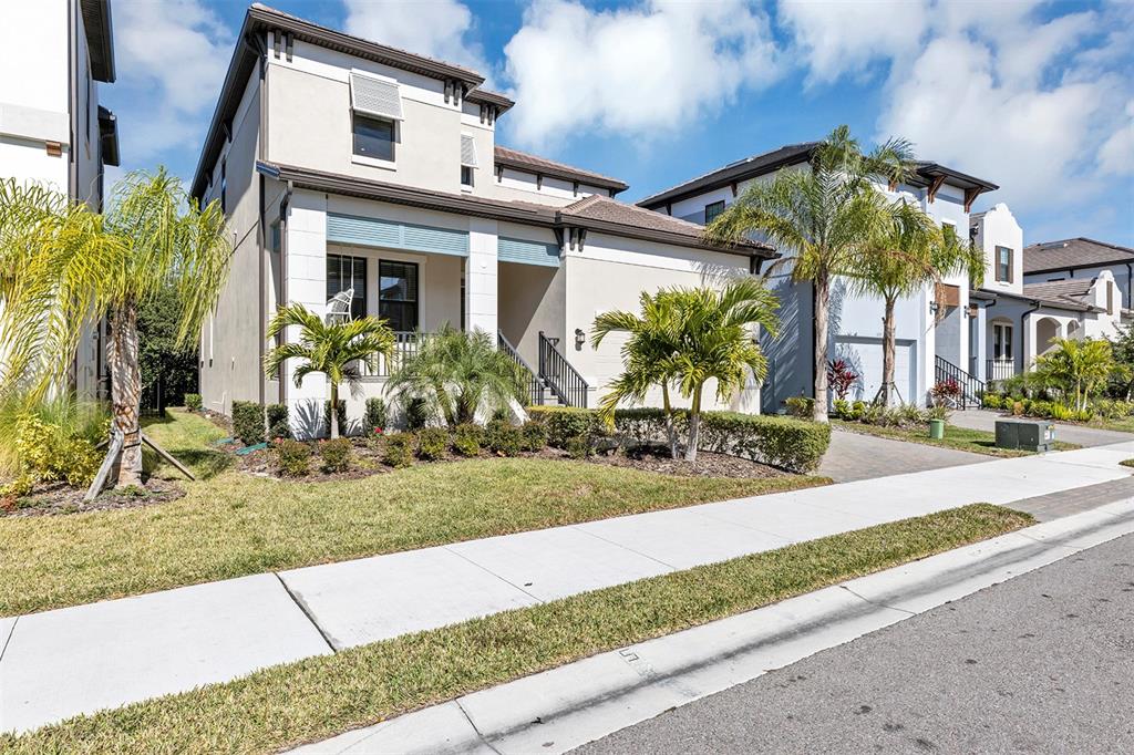 A two-story suburban house with a front porch, palm trees, and a paved driveway — 1115 SEAGRAPE DRIVE, RUSKIN, FL