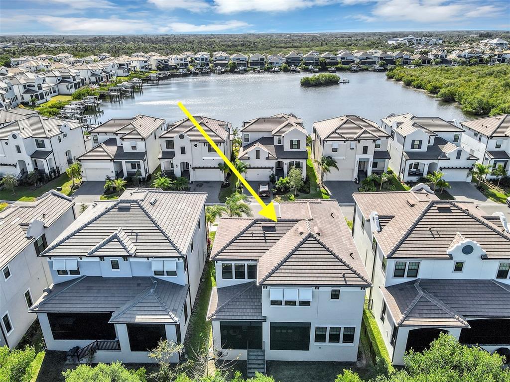An aerial view shows a row of modern houses with tiled roofs near a lake — 1115 SEAGRAPE DRIVE, RUSKIN, FL