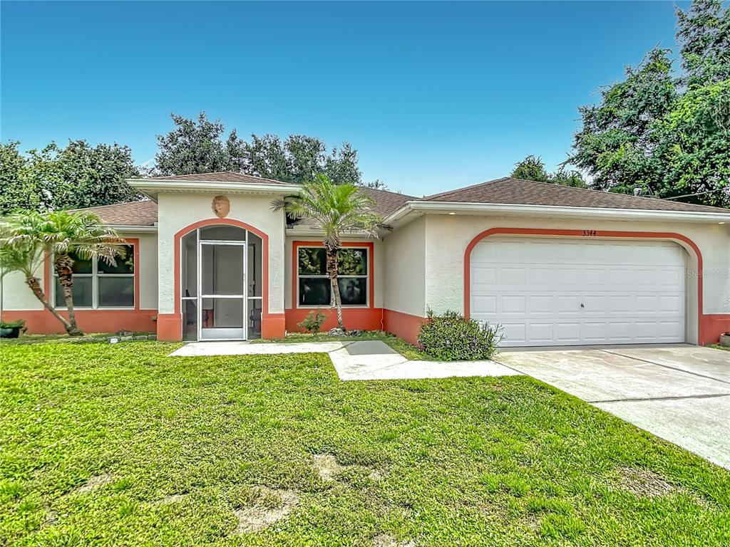 A single-story house with a white stucco exterior, orange trim, and a two-car garage — 3344 PERICLES AVENUE, NORTH PORT, FL