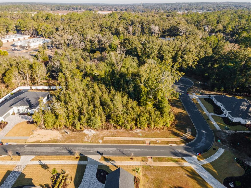 An aerial view shows a wooded residential lot situated between two houses on a paved street — 617 SW 139TH COURT, NEWBERRY, FL
