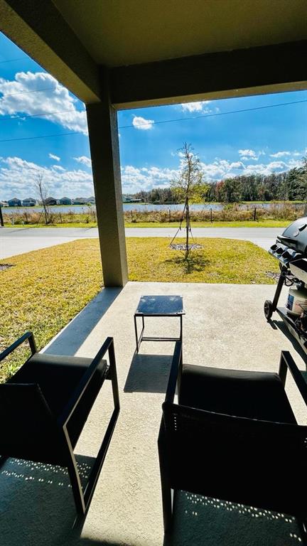 A covered concrete patio features two black chairs, a small side table, and a grill — 11926 SUNSAIL AVENUE, ORLANDO, FL