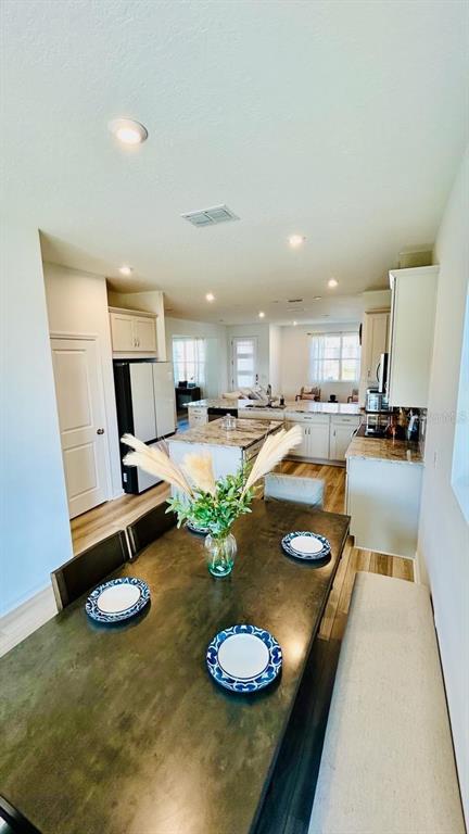 A dining area with a dark wooden table leads into a bright, open-concept kitchen — 11926 SUNSAIL AVENUE, ORLANDO, FL