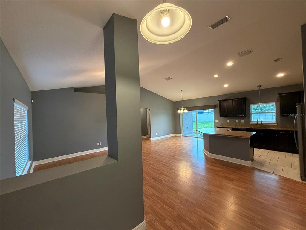 An open-concept living area features dark gray walls, wood-look flooring, and a kitchen with dark cabinetry — 10340 SE 69TH TERRACE, BELLEVIEW, FL