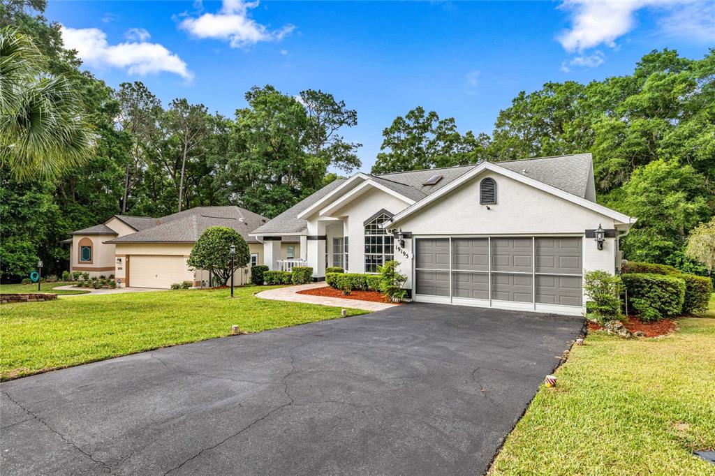 A single-story house with a white stucco exterior, a screened garage, and a paved driveway — 19195 SW 92ND LOOP, DUNNELLON, FL