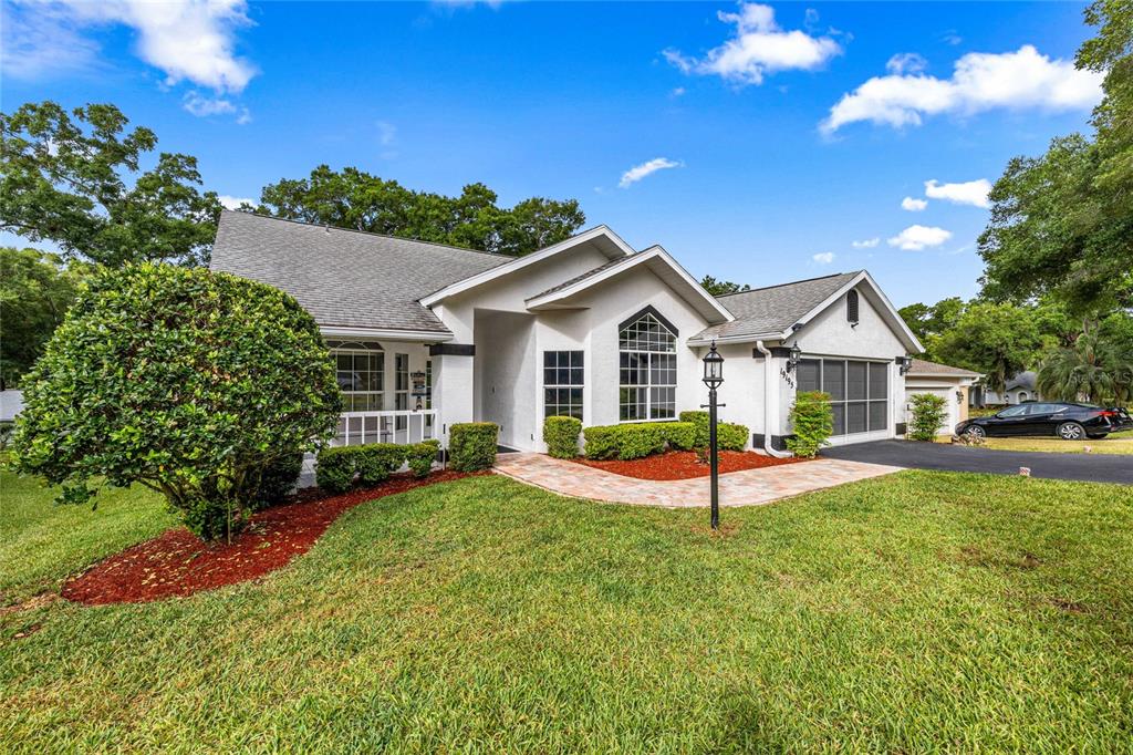 A single-story house with a white stucco exterior, a paved walkway, and a landscaped yard — 19195 SW 92ND LOOP, DUNNELLON, FL