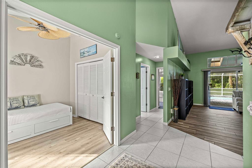 A view from a tiled entryway into a bedroom and a living area with wood floors — 19195 SW 92ND LOOP, DUNNELLON, FL