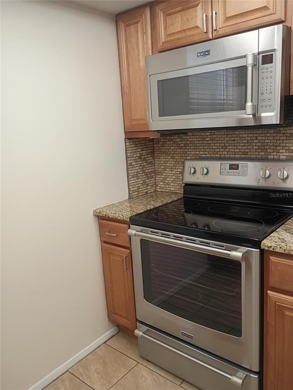 A kitchen features light wood cabinets, stainless steel appliances, granite countertops, and a tiled backsplash — 1520 GLEN OAKS DRIVE E UNIT 248, SARASOTA, FL
