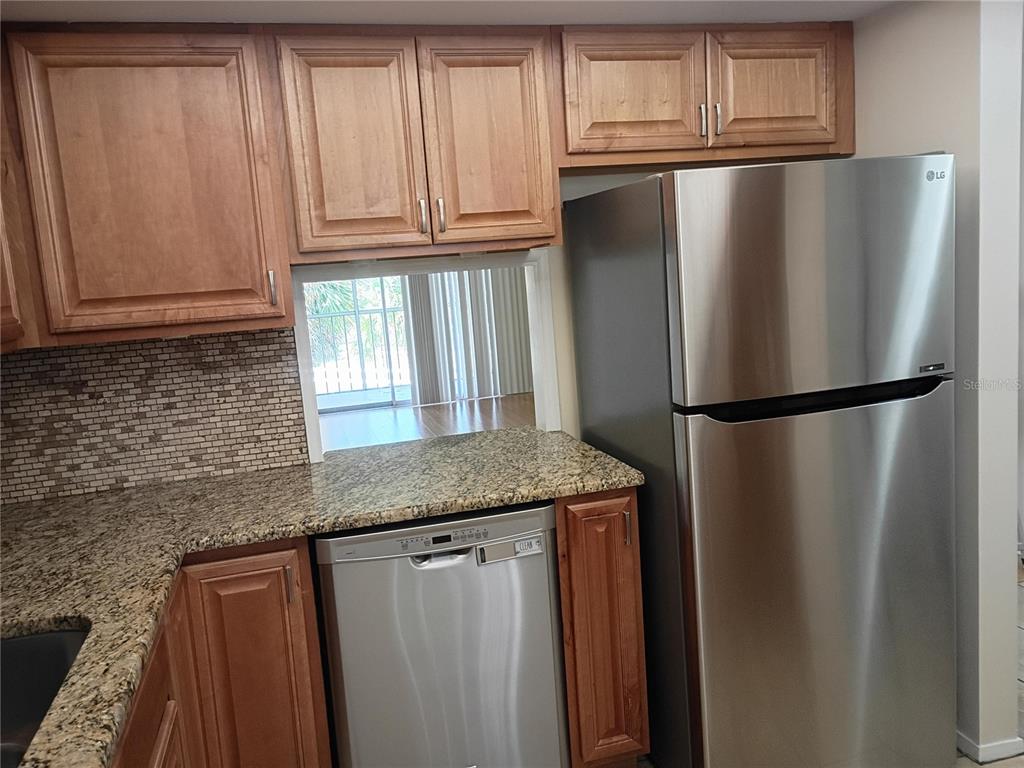 A kitchen features wood cabinets, granite countertops, stainless steel appliances, and a tray ceiling — 1520 GLEN OAKS DRIVE E UNIT 248, SARASOTA, FL