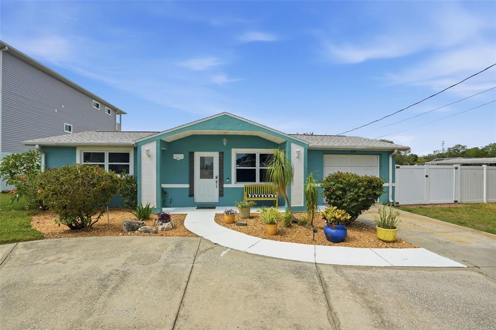 A teal single-story house features a white-trimmed entryway, a front walkway, and a paved driveway — 6907 CLARK STREET, HUDSON, FL