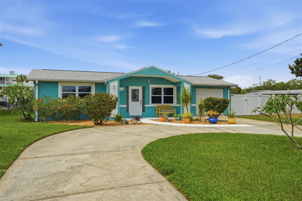 A teal single-story house with a curved concrete driveway and a front yard lawn — 6907 CLARK STREET, HUDSON, FL