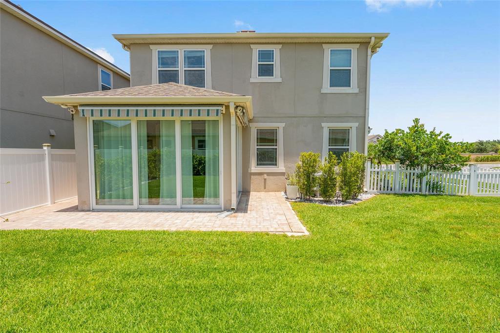 The exterior of a two-story house features a sunroom, a paver patio, and a fenced yard — 2260 RAPOLLO DRIVE, KISSIMMEE, FL