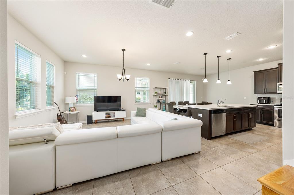 An open-concept living room and kitchen featuring a white sectional sofa and a kitchen island — 2260 RAPOLLO DRIVE, KISSIMMEE, FL