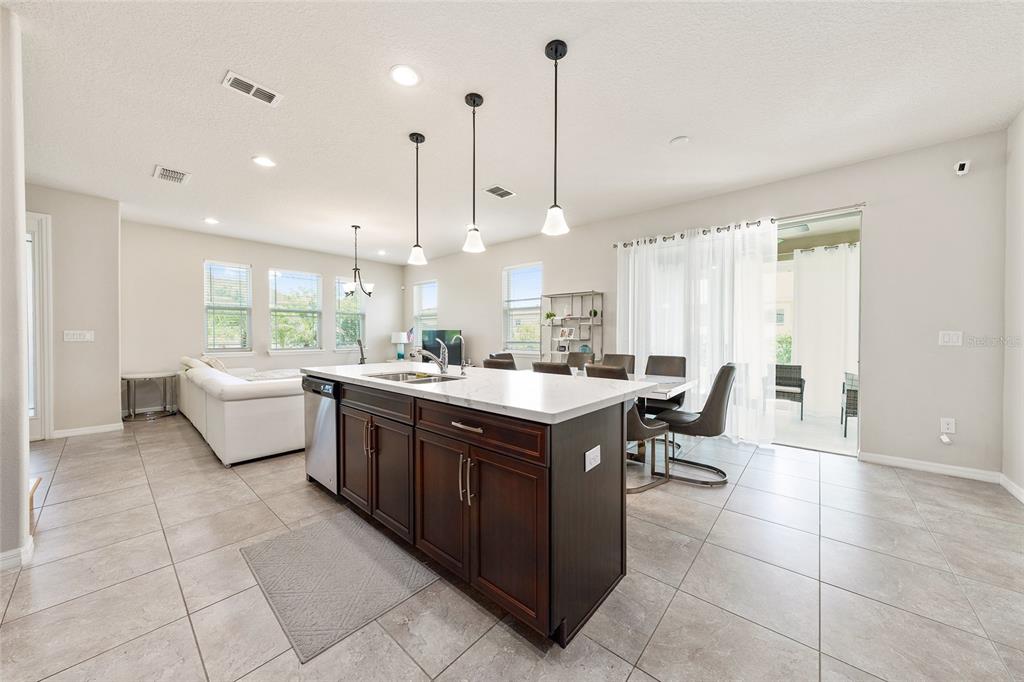 A kitchen island with dark wood cabinets and white countertops sits in an open-concept living area — 2260 RAPOLLO DRIVE, KISSIMMEE, FL
