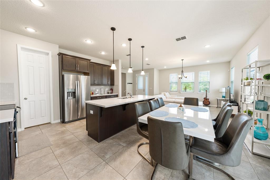 A kitchen with dark cabinets and a white island opens into a dining area — 2260 RAPOLLO DRIVE, KISSIMMEE, FL