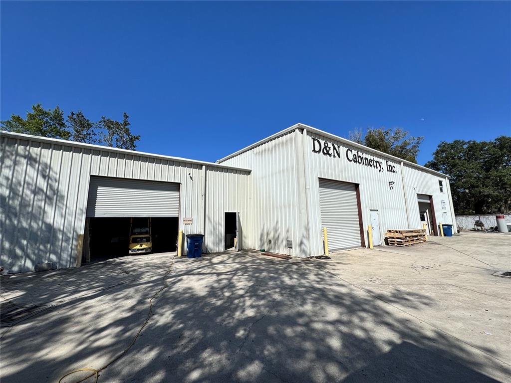 The exterior of a metal industrial building features two large roll-up doors and signage — 2914 KENILWORTH BOULEVARD, SEBRING, FL