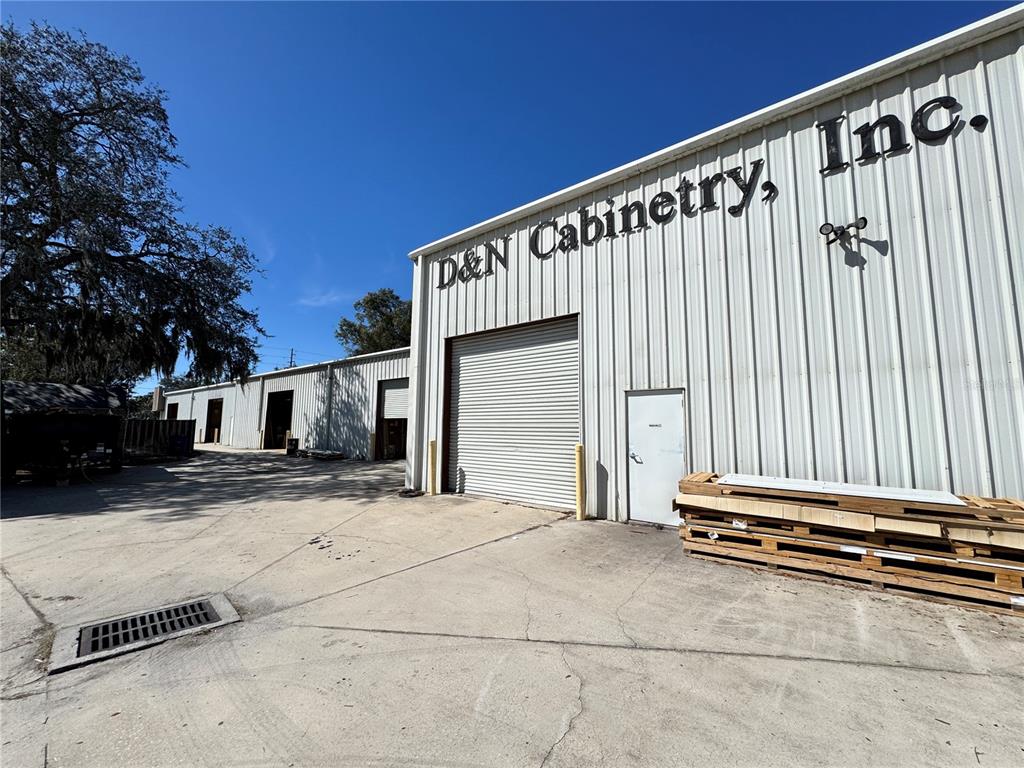 The exterior of a metal industrial building features a roll-up door and a pedestrian entrance — 2914 KENILWORTH BOULEVARD, SEBRING, FL