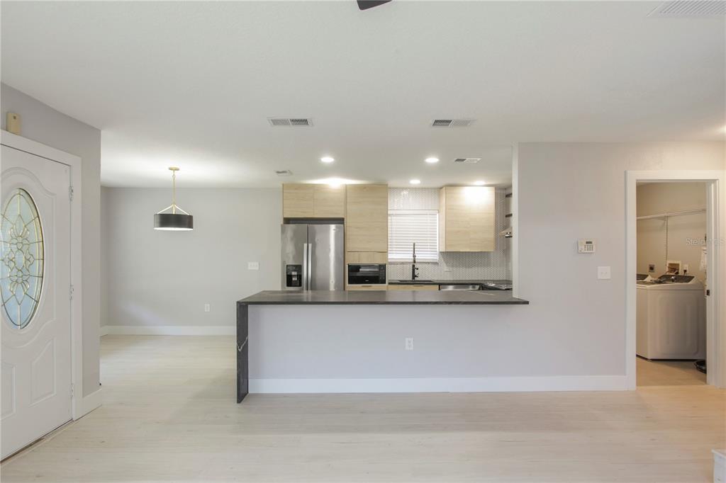 A kitchen with light wood cabinets, a dark countertop, and an adjacent laundry room — 822 POLK STREET, ORLANDO, FL