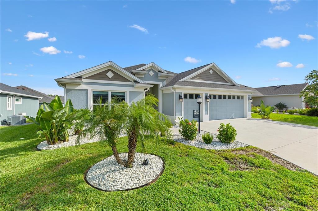 A light blue single-story house with a two-car garage and landscaped front yard — 575 RANDALL ROAD, THE VILLAGES, FL