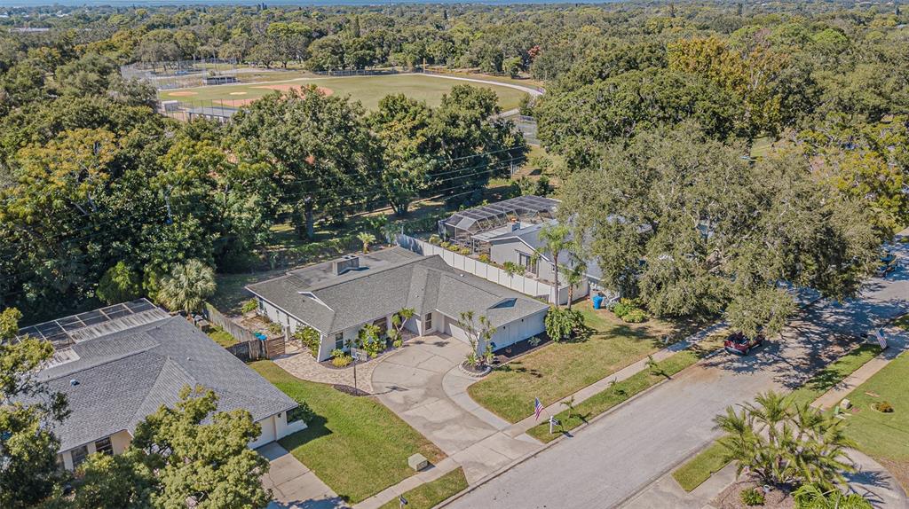 An aerial view shows a suburban house with a paved driveway and a nearby baseball field — 565 SANDY HOOK ROAD, PALM HARBOR, FL