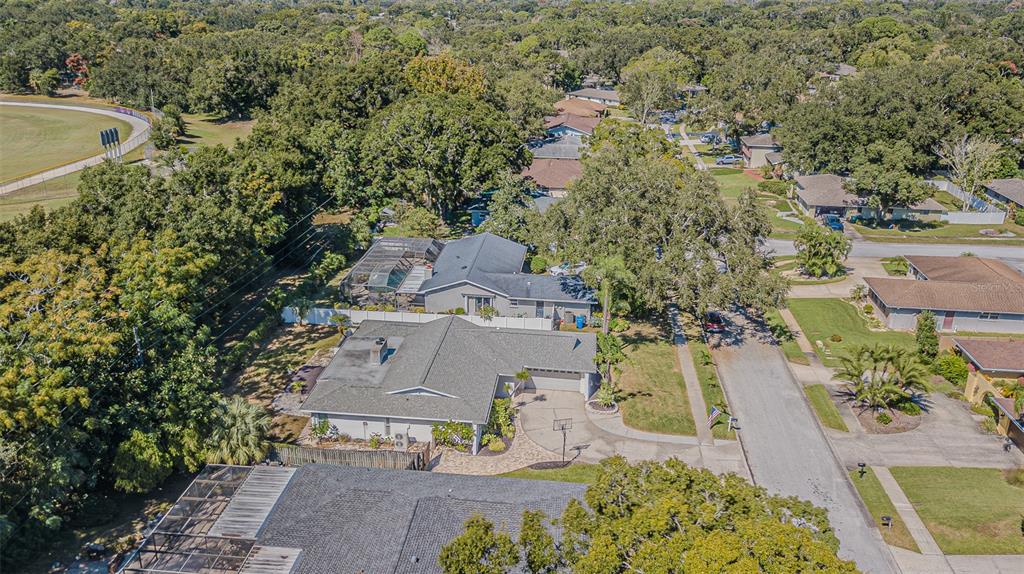 An aerial view shows a suburban house with a gray roof, driveway, and pool enclosure — 565 SANDY HOOK ROAD, PALM HARBOR, FL