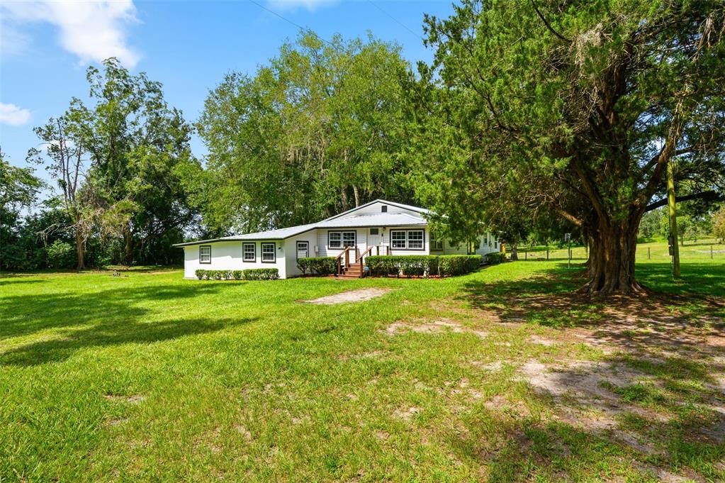 A white, single-story house with a metal roof sits on a large, grassy lot — 6218 SW 202ND STREET, NEWBERRY, FL