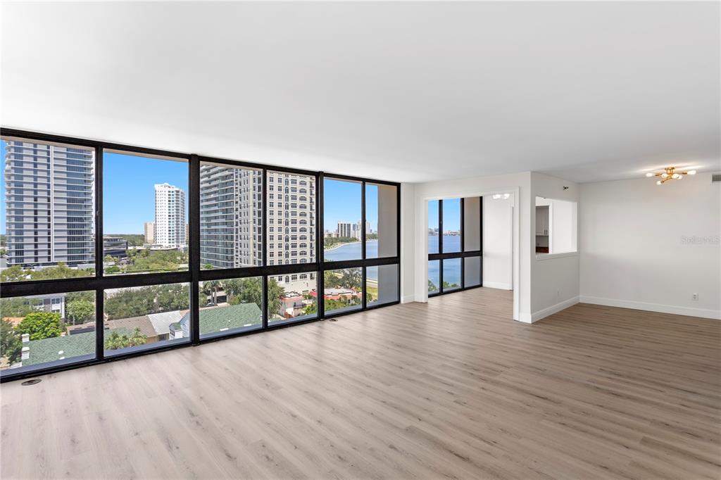 A bright living room features light wood flooring, floor-to-ceiling windows, and views of the water — 3301 BAYSHORE BOULEVARD UNIT 1101E, TAMPA, FL