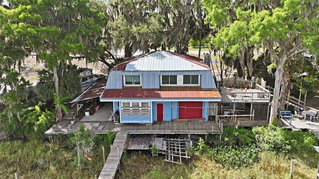 An aerial view of a blue two-story house with a metal roof and wooden deck — 400 LAKESHORE DRIVE, EUSTIS, FL