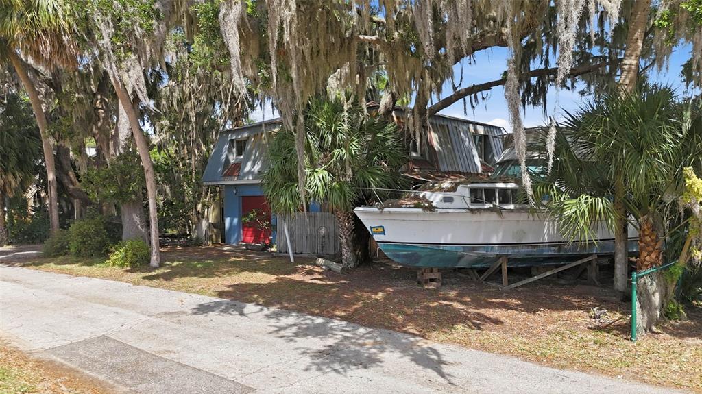 A boat sits on blocks in the yard of a house with a blue garage — 400 LAKESHORE DRIVE, EUSTIS, FL