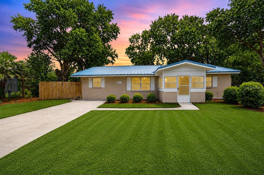 A single-story house with a blue metal roof and a concrete driveway sits on grass — 205 2ND AVENUE SE, RUSKIN, FL