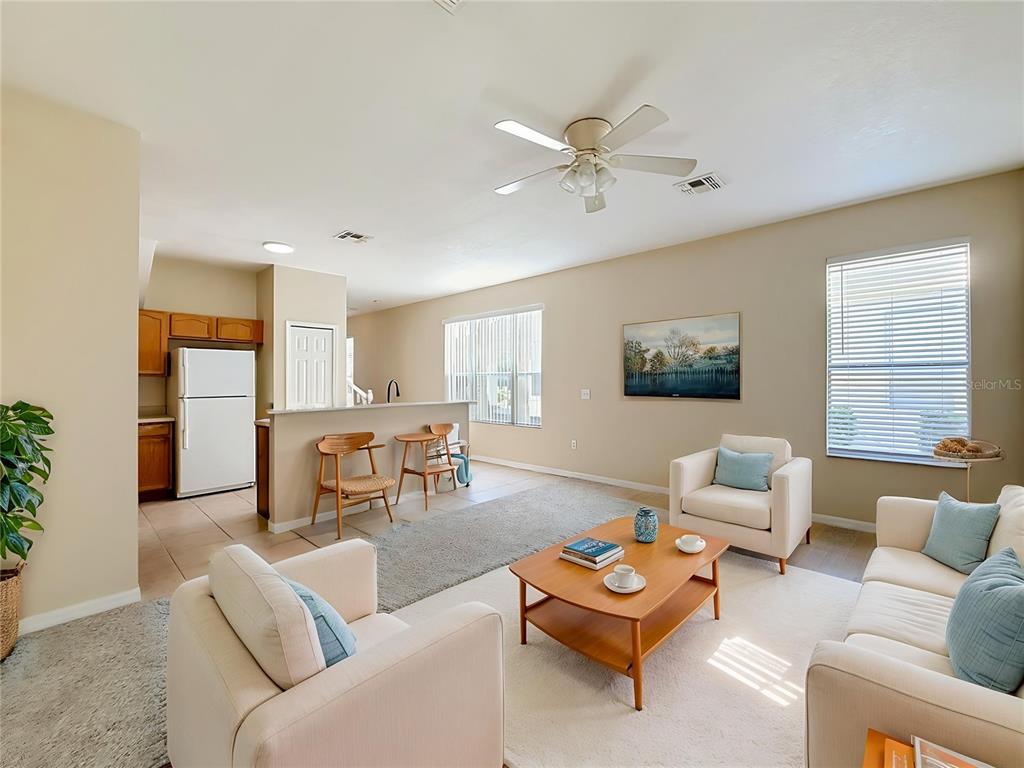 A living room with light-colored furniture, a wooden coffee table, and an adjacent kitchen area — 17508 BLESSING DRIVE, CLERMONT, FL