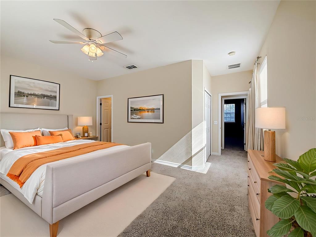 A bedroom features a bed with orange bedding, a dresser, and a ceiling fan — 17508 BLESSING DRIVE, CLERMONT, FL
