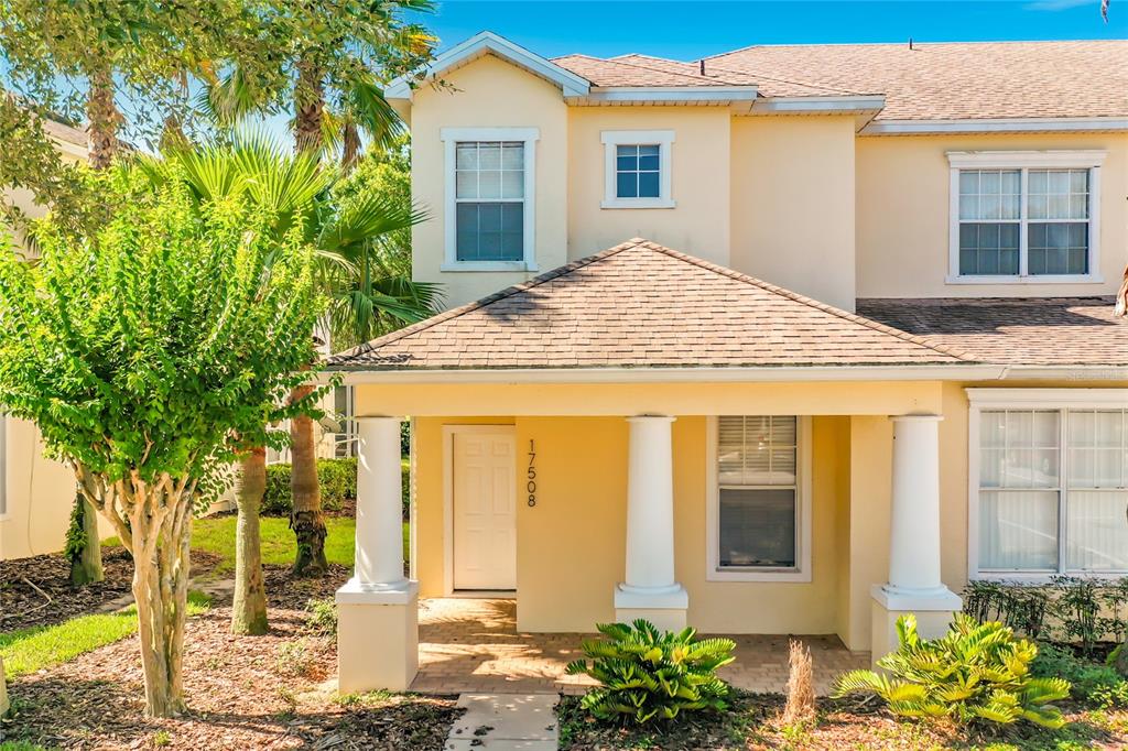 A two-story yellow house features a covered front porch with white columns and landscaping — 17508 BLESSING DRIVE, CLERMONT, FL