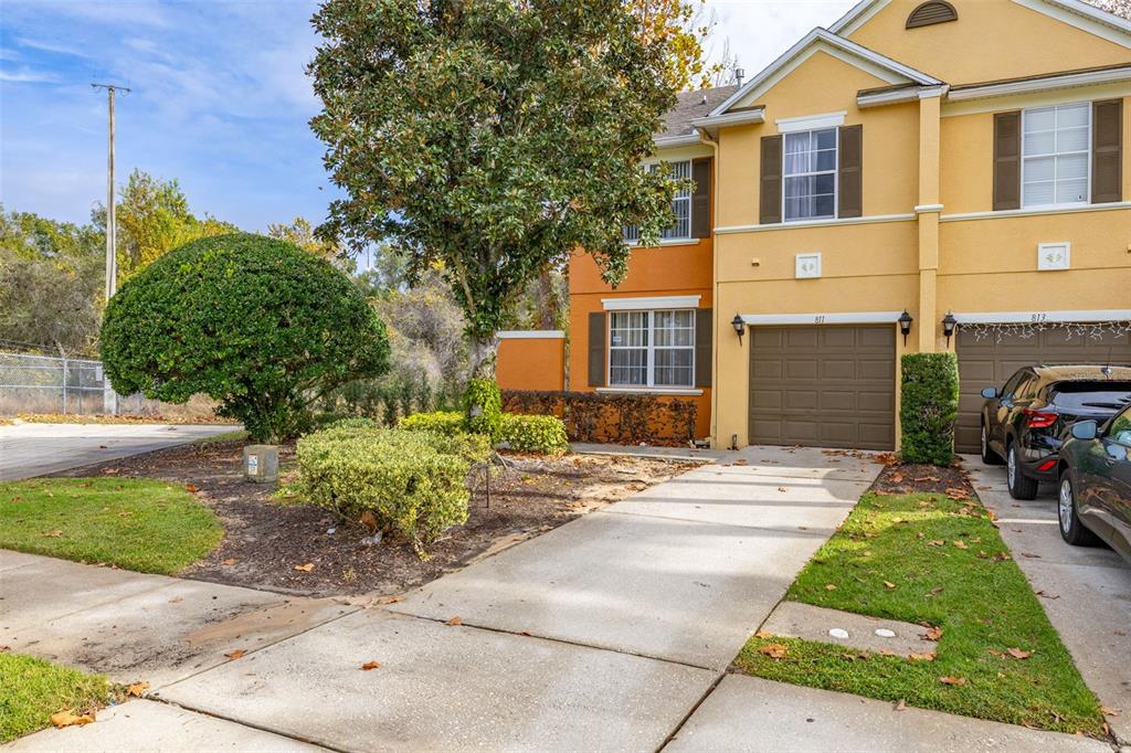A two-story townhouse with a brown garage, beige siding, and a small front yard — 811 ASSEMBLY COURT, REUNION, FL