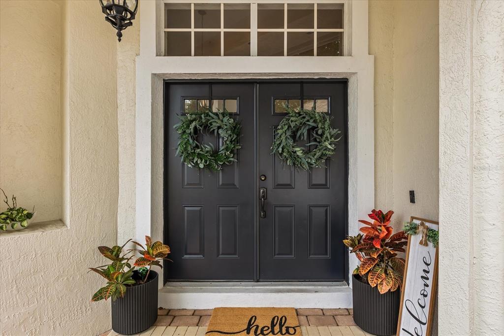 A front entryway features double black doors with wreaths, potted plants, and a welcome sign — 1934 THOROUGHBRED DRIVE, GOTHA, FL
