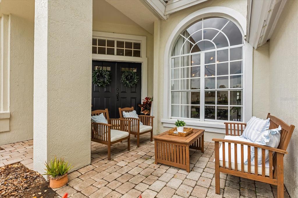 A paved front porch features three wooden chairs, a coffee table, and a black double door — 1934 THOROUGHBRED DRIVE, GOTHA, FL