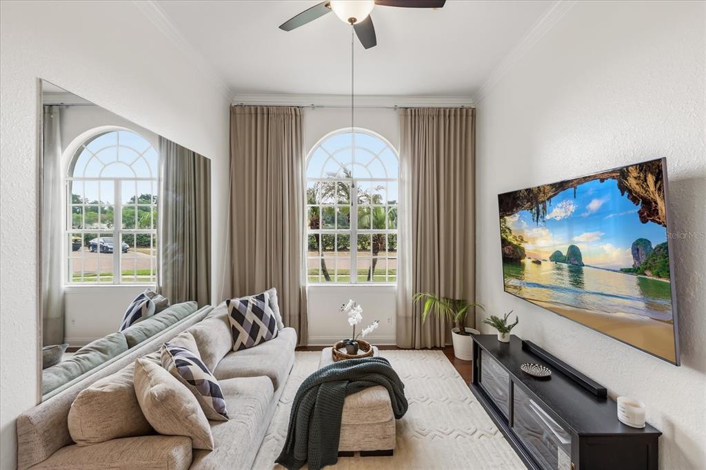 A living room features a sofa, a wall-mounted television, and large arched windows — 1934 THOROUGHBRED DRIVE, GOTHA, FL