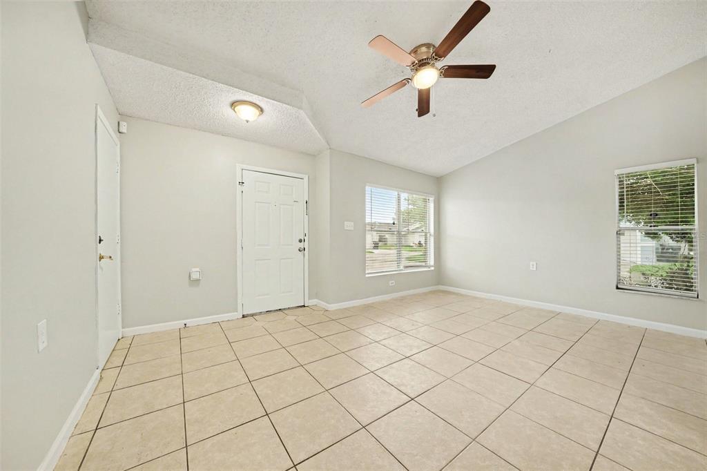 An empty room with light-colored tile flooring, a vaulted ceiling, and a ceiling fan — 1034 CLOVERCREST ROAD, ORLANDO, FL