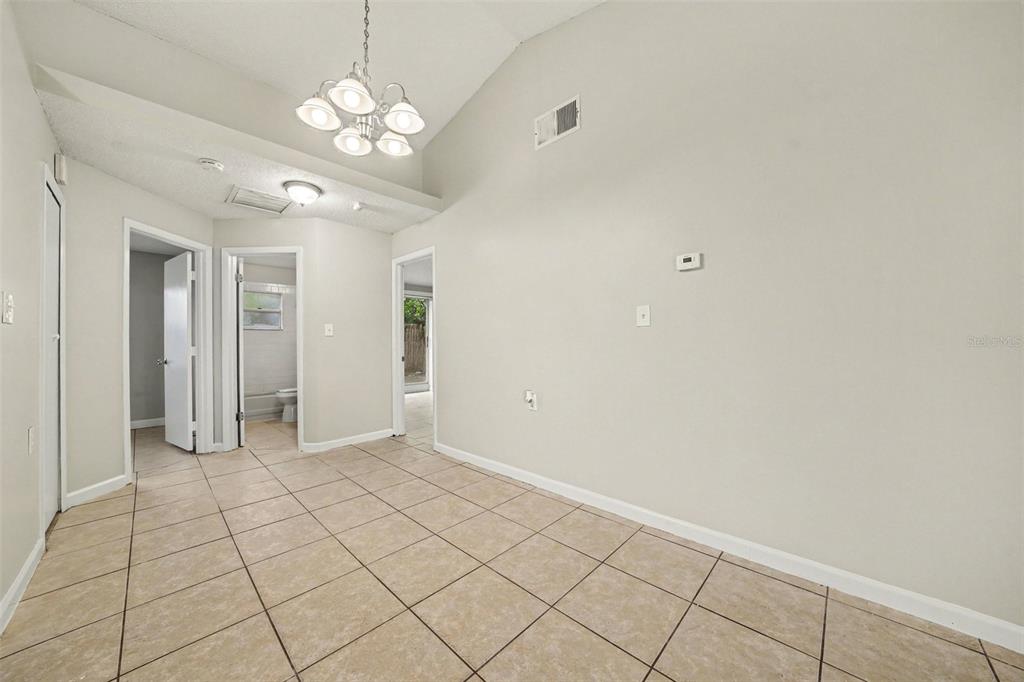 An interior room with light-colored walls, tiled flooring, a vaulted ceiling, and a chandelier — 1034 CLOVERCREST ROAD, ORLANDO, FL