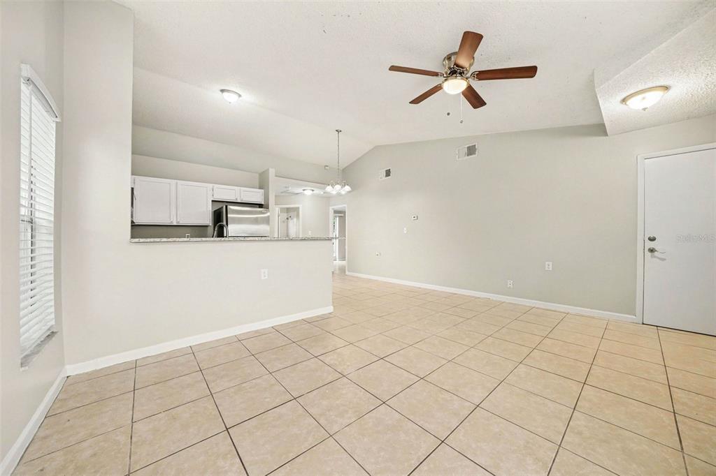 An open-concept living area features light tile flooring, white kitchen cabinets, and a ceiling fan — 1034 CLOVERCREST ROAD, ORLANDO, FL