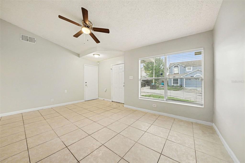 An empty room with beige tile flooring, a ceiling fan, and a large window — 1034 CLOVERCREST ROAD, ORLANDO, FL