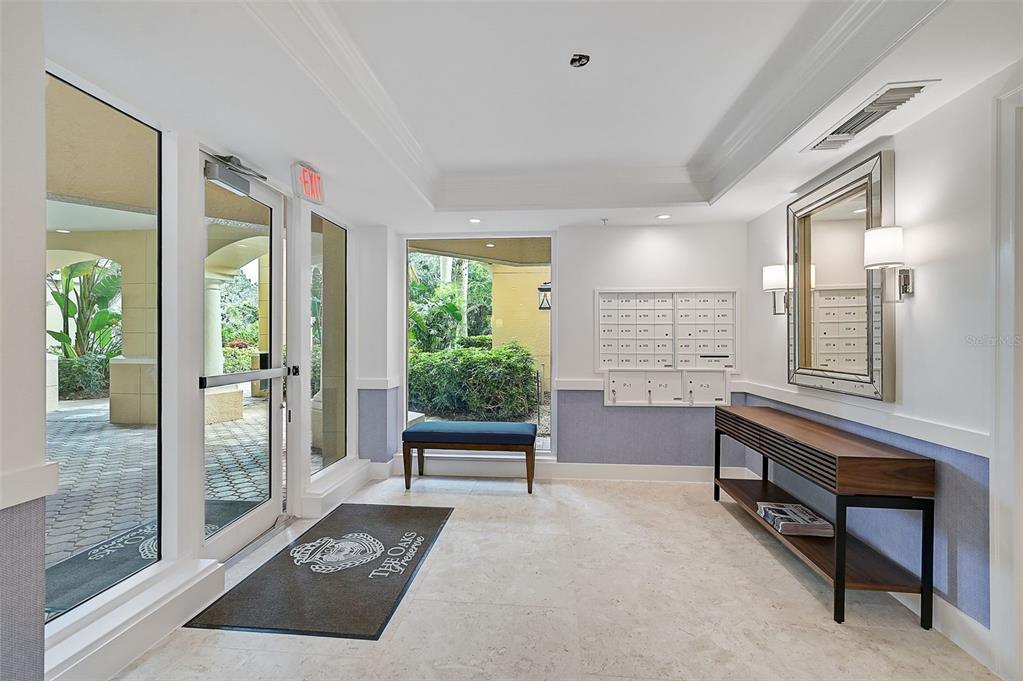 An apartment building lobby features a mail station, a console table, and glass entry doors — 409 N POINT ROAD UNIT 502, OSPREY, FL