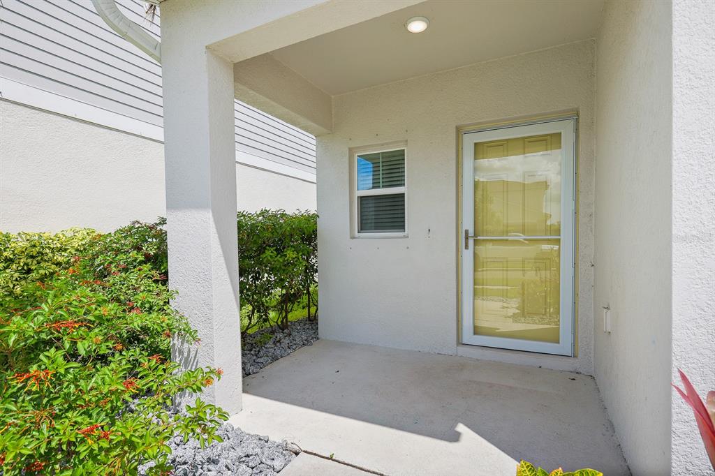 A covered concrete porch features a white storm door and a small window — 12894 FRENCH MARKET DRIVE, RIVERVIEW, FL