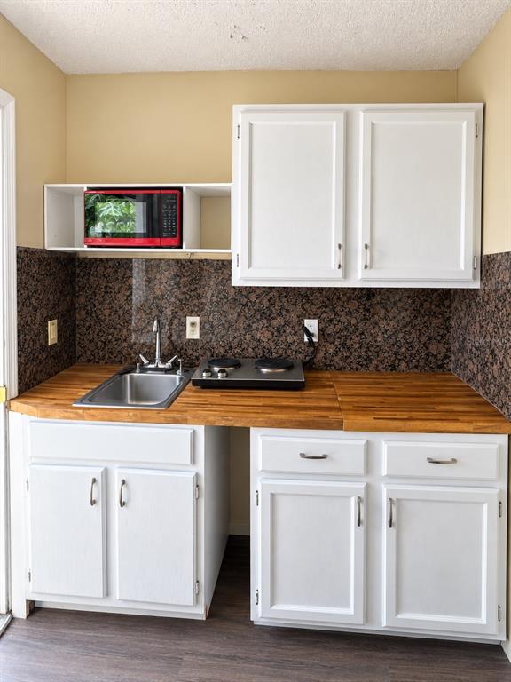 A small kitchen features white cabinets, a wood countertop, a sink, and a red microwave — 440 BERWICK CIRCLE UNIT 2, DELAND, FL
