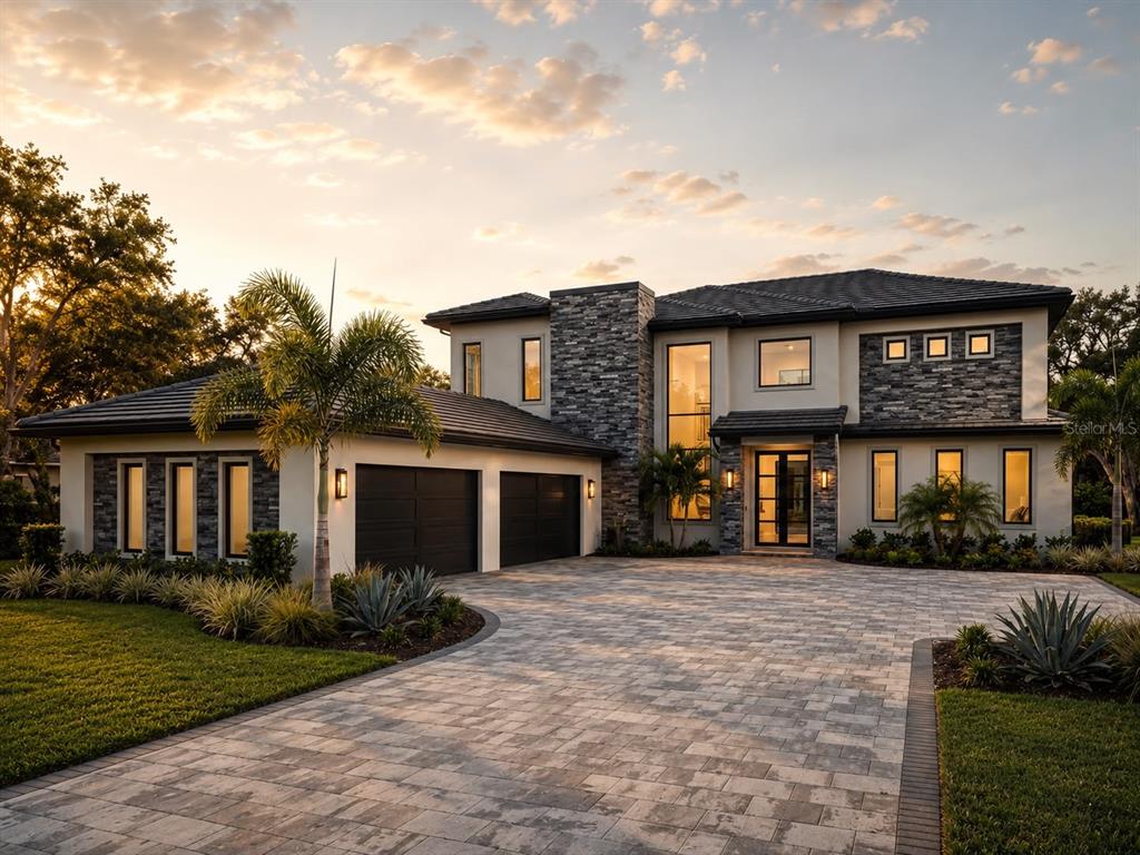 A two-story modern house with a stone facade, dark roof, and a paved driveway — 16748 ARTIMINO LOOP, MONTVERDE, FL