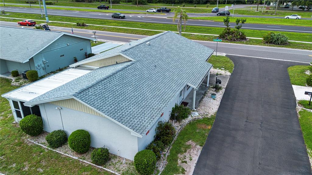 An aerial view shows a light-colored house with a shingled roof and an asphalt driveway — 701 READING PLACE, SUN CITY CENTER, FL