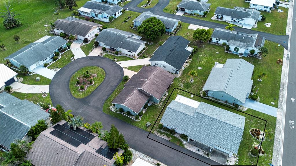 An aerial view shows a suburban neighborhood with houses, driveways, and a circular cul-de-sac — 701 READING PLACE, SUN CITY CENTER, FL