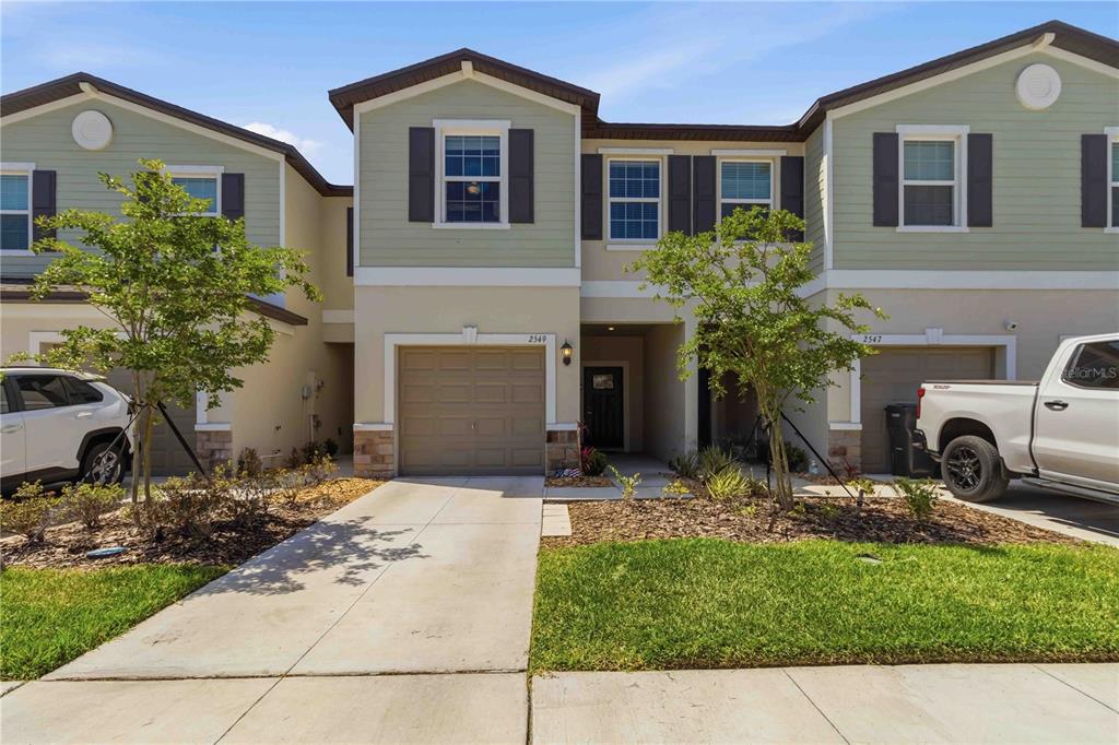 A two-story townhouse exterior features a tan stucco base, light green siding, and a garage — 2549 SUNRAY VENUS WAY, RUSKIN, FL