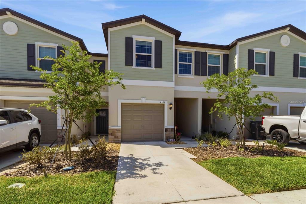 A two-story townhouse exterior features a single-car garage, light green siding, and a concrete driveway — 2549 SUNRAY VENUS WAY, RUSKIN, FL